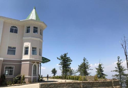 a white house with a green roof at Club Mahindra Pristine Peaks Naldehra in Shimla