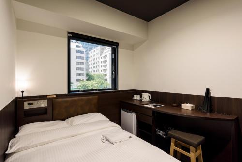 a bedroom with a bed and a desk and a window at Belken Hotel Tokyo in Tokyo