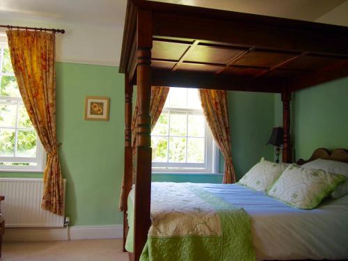 a bedroom with a canopy bed with green walls at Wrangham House in Filey