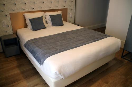 a large bed with two pillows on top of it at Hotel Saint Vincent in Lyon
