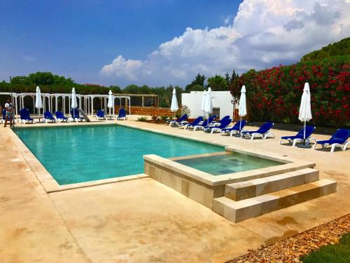 a swimming pool with blue chairs and umbrellas at RELAIS MASSERIA CASINA DEI CARI in Presicce