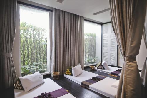 zwei Betten in einem Zimmer mit großen Fenstern in der Unterkunft The Raweekanlaya Bangkok in Bangkok
