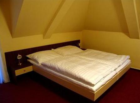 Cama pequeña en habitación con pared amarilla en Hotel Altenberg en Staré Hory