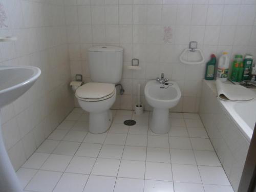 a white bathroom with a toilet and a sink at Sea Sight Apartment in Vila Chã