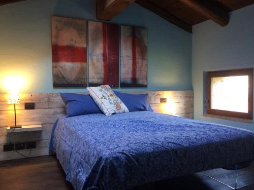 Un dormitorio con una cama azul y una ventana en La Casa Ponca, en Cormòns