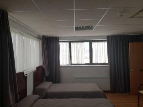 um quarto de hotel com duas camas e duas janelas em Pension La Espiga em Pamplona