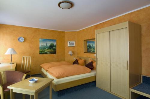 マイセンにあるHotel Schlossbergのベッドルーム1室(オレンジのシーツとテーブル付きのベッド1台付)