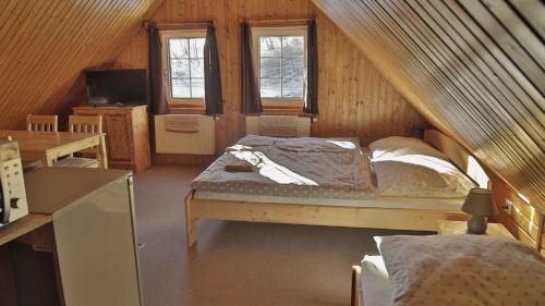 a bedroom with a bed in a attic with windows at Penzion Ostruznik in Ostružná