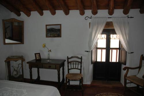 a bedroom with a bed and a table and a window at Villa del Municipal in Villaluenga del Rosario