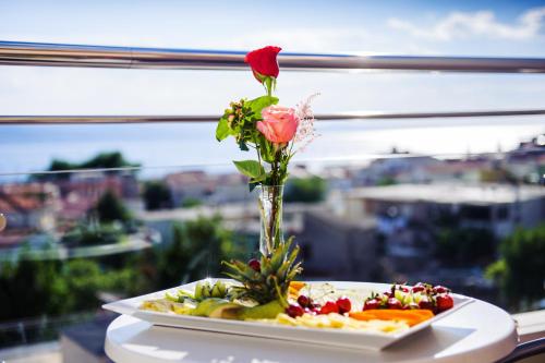 a vase with a rose and a plate of food at Villa Palloma in Baška Voda