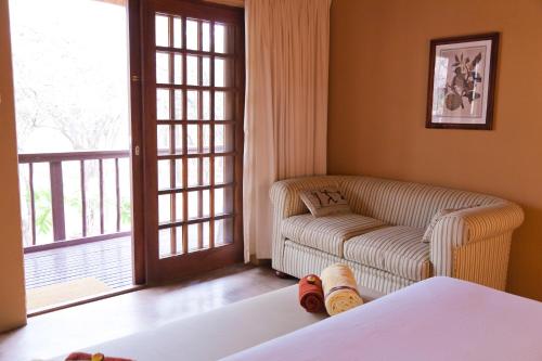 a living room with a couch and a chair and window at Needles Lodge in Marloth Park
