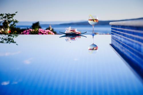 a glass of wine sitting on the edge of a swimming pool at Villa Palloma in Baška Voda