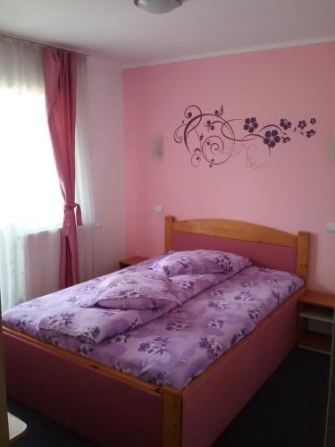 a bedroom with a bed with purple sheets and flowers on the wall at Pensiune Restaurant Sfinx in Buşteni