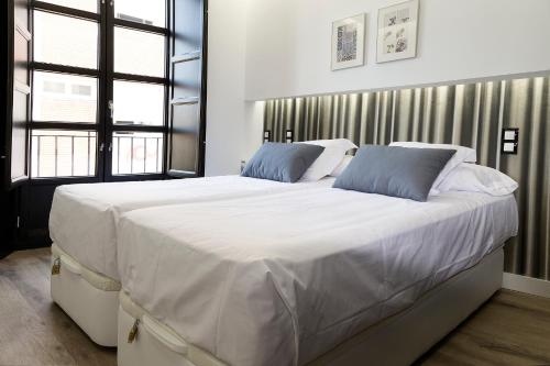 a large white bed with blue pillows in a bedroom at La Tinaja del Realejo in Granada