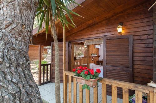 a porch of a wooden house with flowers on it at Tenuta del Barco WineRestaurant and Hospitality in Pulsano