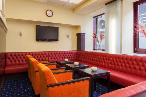 a waiting room with red booths and a flat screen tv at Best Western Hotel Augusta in Augsburg
