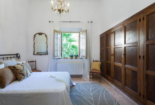 1 dormitorio con cama, ventana y lámpara de araña en Villa Maresme, en Cabrils