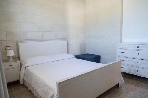 Un pequeño dormitorio con una cama blanca y un tocador en Masseria 25 Anni en Laterza