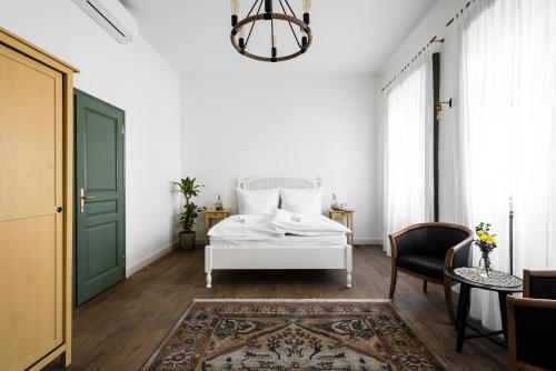 a bedroom with a white bed and a green door at R40 Vendégház in Mád
