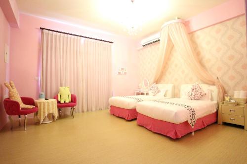a bedroom with two beds and two red chairs at Aunt's Bed and Breakfast in Taitung City