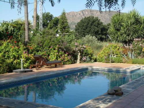 einen Pool in einem Garten mit einer Bank und Blumen in der Unterkunft La Finca Blanca in Alora