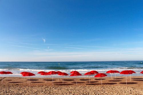 a group of red umbrellas on the beach at URH Sitges Playa in Sitges