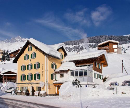 una casa cubierta de nieve frente a una montaña en Hotel Posta, en Sedrun