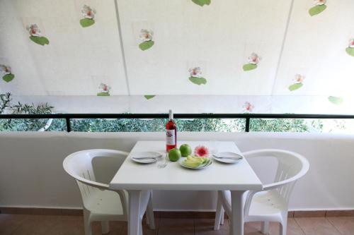 a white table and chairs with a bottle and fruit on it at Nikolas Studios in Agios Nikitas