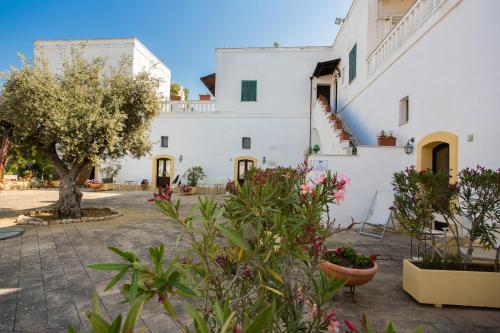 a large white building with plants in the courtyard at Tenuta del Barco WineRestaurant and Hospitality in Pulsano
