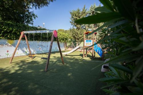 two swings in a park next to a beach at Tenuta del Barco WineRestaurant and Hospitality in Pulsano