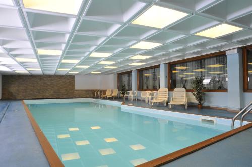 a large swimming pool with a ceiling and chairs at Hotel Tyrolia in Malga Ciapela