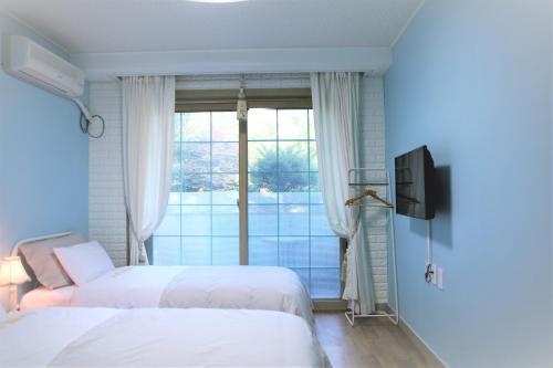 two beds in a room with a window at Shinevalley Pension & Hotel in Pyeongchang 