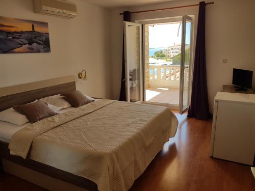 a bedroom with a large bed and a balcony at Pansion Marco Polo in Petrcane