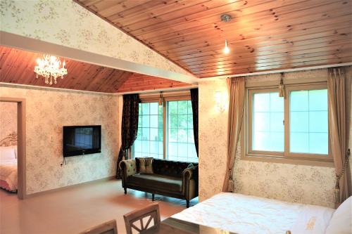 a living room with a couch and a tv at Shinevalley Pension & Hotel in Pyeongchang 