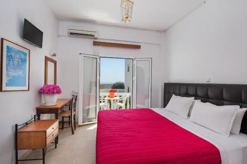 a bedroom with a large bed with a red blanket at Pension Ptolemeos in Fira