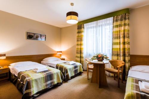 a hotel room with two beds and a table at Hotel City SM Business & Spa in Kraków