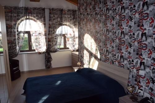 a bedroom with a blue bed and two windows at Tenuta Ferrara in Altavilla Silentina
