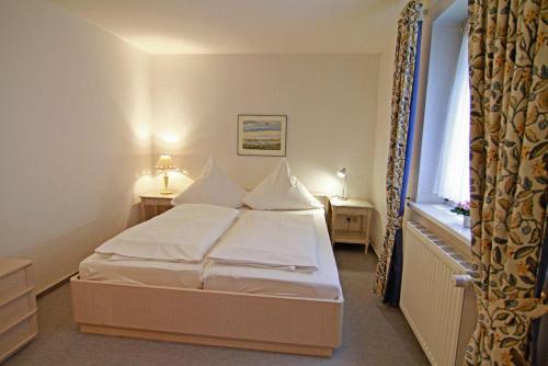 Schlafzimmer mit einem Bett mit weißer Bettwäsche und einem Fenster in der Unterkunft Haus Meisennest, Wohnung Star in Westerland