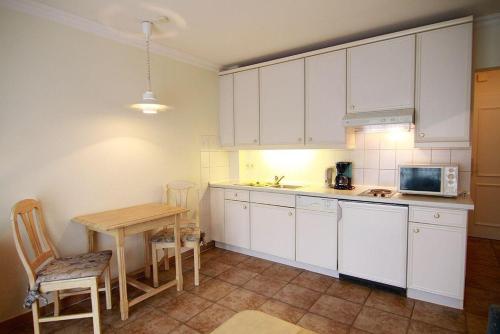 eine Küche mit weißen Schränken, einem Tisch und einer Mikrowelle in der Unterkunft Haus Meisennest, Wohnung Möwe in Westerland