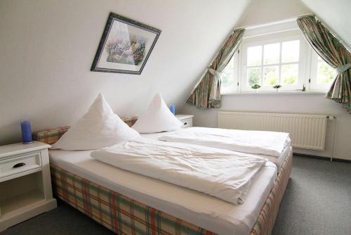 Schlafzimmer mit einem Bett mit weißer Bettwäsche und einem Fenster in der Unterkunft Haus Meisennest, Wohnung Adler in Westerland