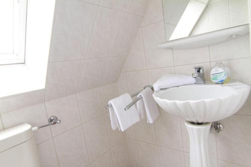 ein weißes Badezimmer mit einem Waschbecken und einem Spiegel in der Unterkunft Haus Meisennest, Wohnung Adler in Westerland
