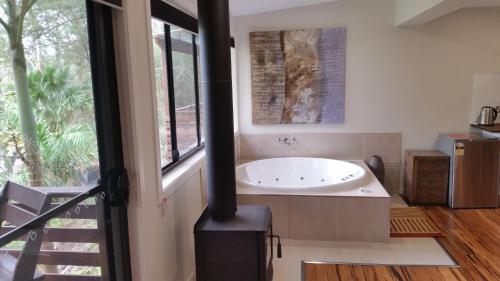 a bathroom with a bath tub sitting next to a window at Alaya Ascend in Eudlo