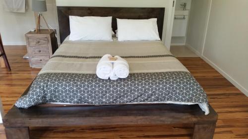 a bedroom with a bed with two white shoes on it at Alaya Ascend in Eudlo