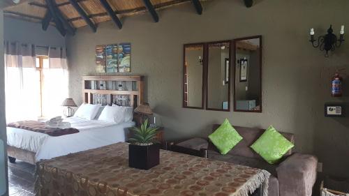 a bedroom with a bed and a couch and mirrors at Warembo Lodge in Grootvlei