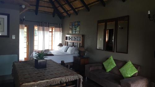 a bedroom with a bed and a table and a couch at Warembo Lodge in Grootvlei
