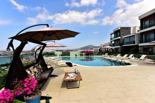 a patio with a table and an umbrella next to a pool at Degirmenburnu Residence in Bodrum City