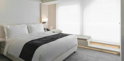a bedroom with a large white bed and a window at Swiio Hotel Daan in Taipei