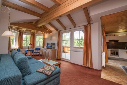 a living room with a blue couch and a kitchen at Landhaus Charlotte Apartments Tirol in Seefeld in Tirol