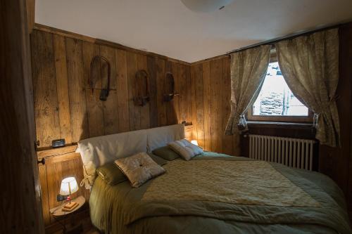 a bedroom with a bed with wooden walls and a window at Bellavista Cogne Apartment in Cogne