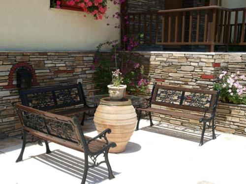 two benches and a planter in front of a brick wall at Hotel Markos in Ierissos